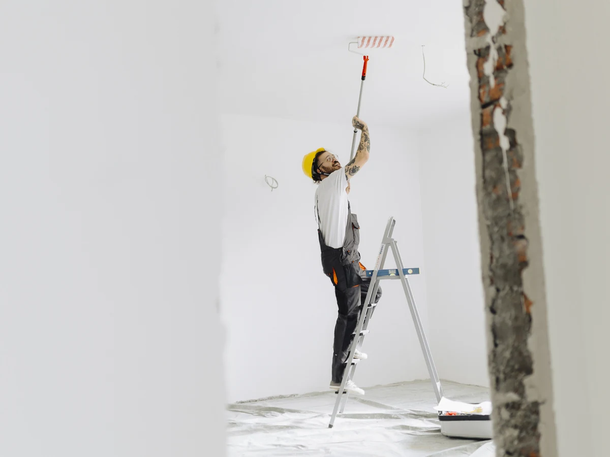 painting-decorating-worker-ladder-rolling-bradford-decorators A decorator on a stepladder rolling paint onto a ceiling in an empty room